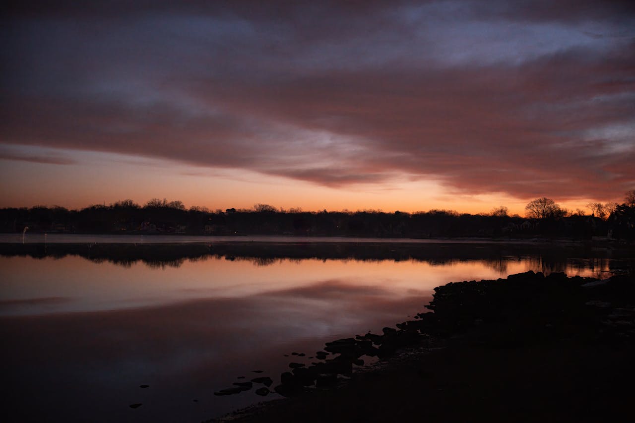 Beautiful winter sunrise at Holly Pond in Stamford, CT with pink skies and calm waters.