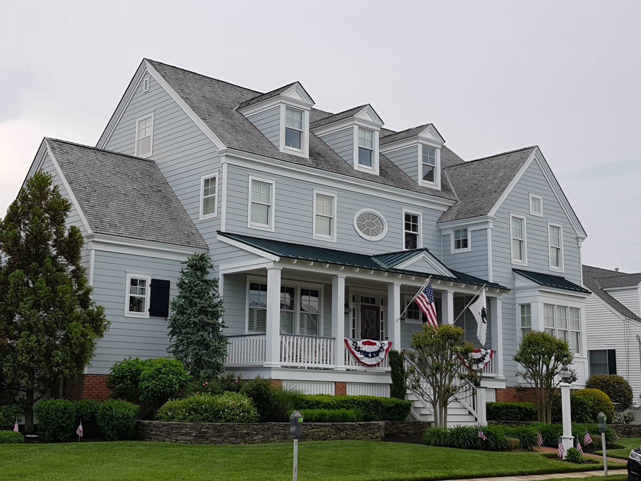 Elegant colonial-style house in Cape May, NJ with manicured lawn and American flags.