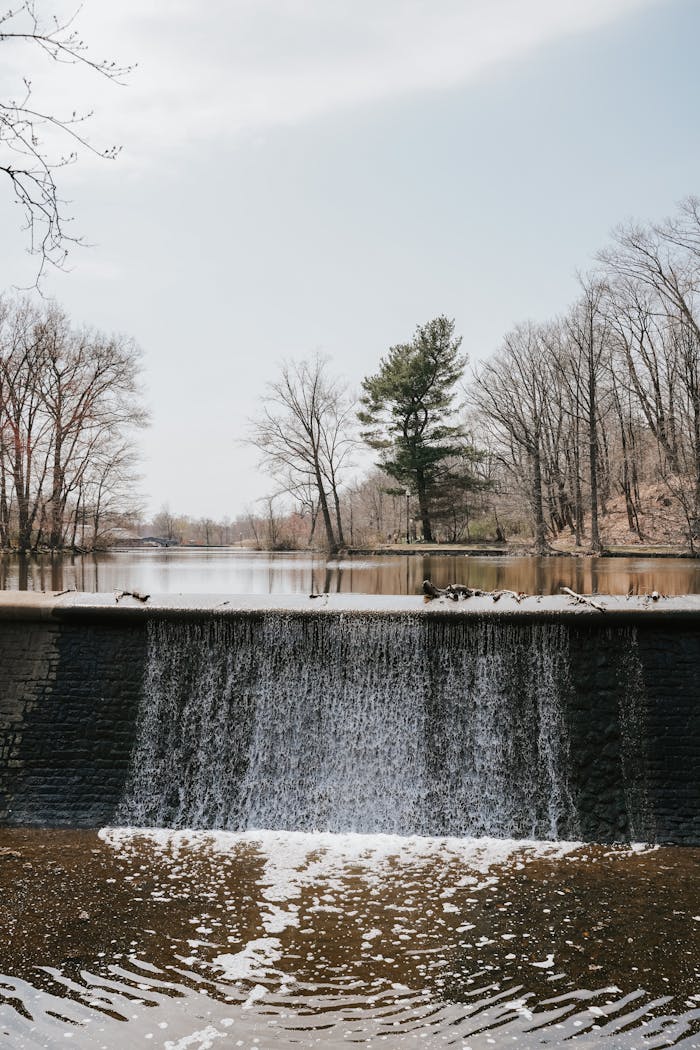 Serene waterfall cascading over a dam surrounded by winter trees in Verona Park, NJ.